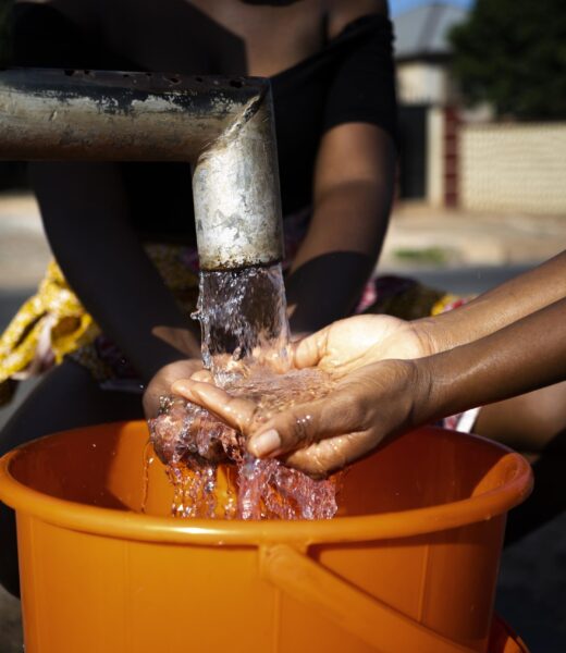 african-woman-pouring-water-recipient-outdoors