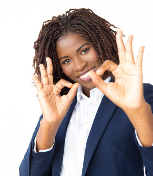 Businesswoman showing ok sign and smiling at camera. Portrait of cheerful young African American businesswoman showing ok sign and looking at camera. Approving concept